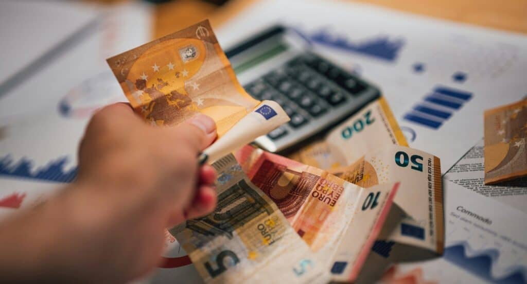 Hand holding cards and cash representing budget planning